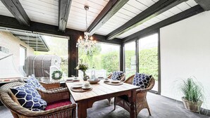A dining area with a wooden table, wicker chairs, and a chandelier. - Vacation apartment Kerstin - The vacation home Kerstin offers you with approx110m² a lot of space. (Sylt)