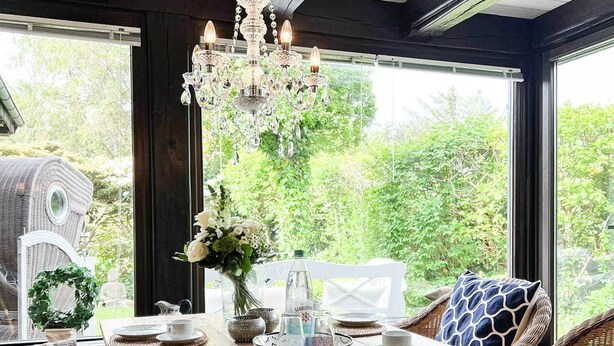 A wooden dining table set with plates, cups, and a chandelier. - Vacation apartment Kerstin - The vacation home Kerstin offers you with approx110m² a lot of space. (Sylt)