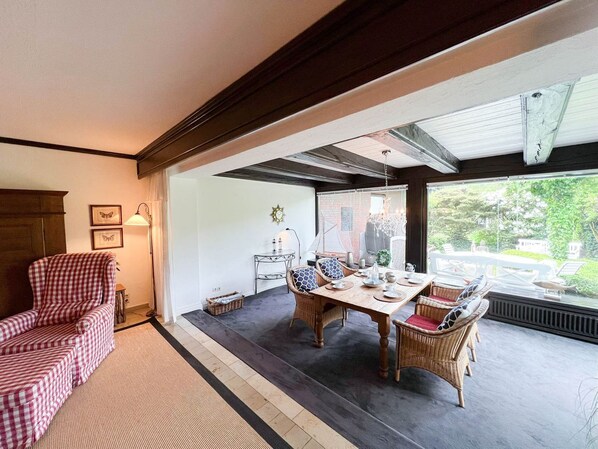 A dining area with a wooden table, wicker chairs, and a view of the outdoors.