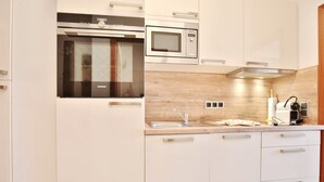 A modern kitchen with a built-in oven, microwave, and stainless steel sink.