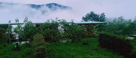 A bridge over a body of water with a mountainous backdrop and dense greenery in the foreground.