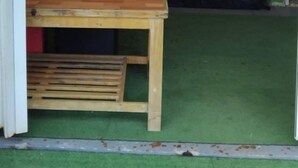 Una tienda de campaña con una cama y una mesa, césped artificial verde y una lámpara colgante.