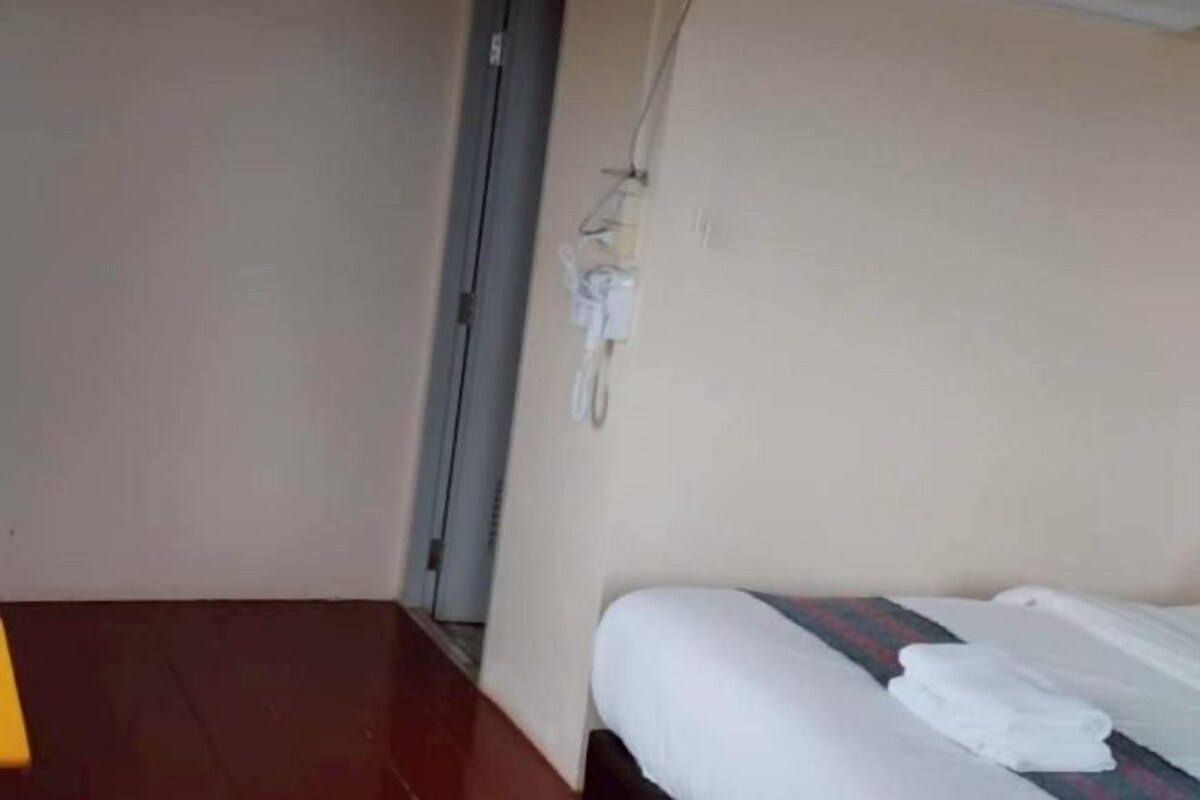 A hotel room with a bed, a small table, and a door.