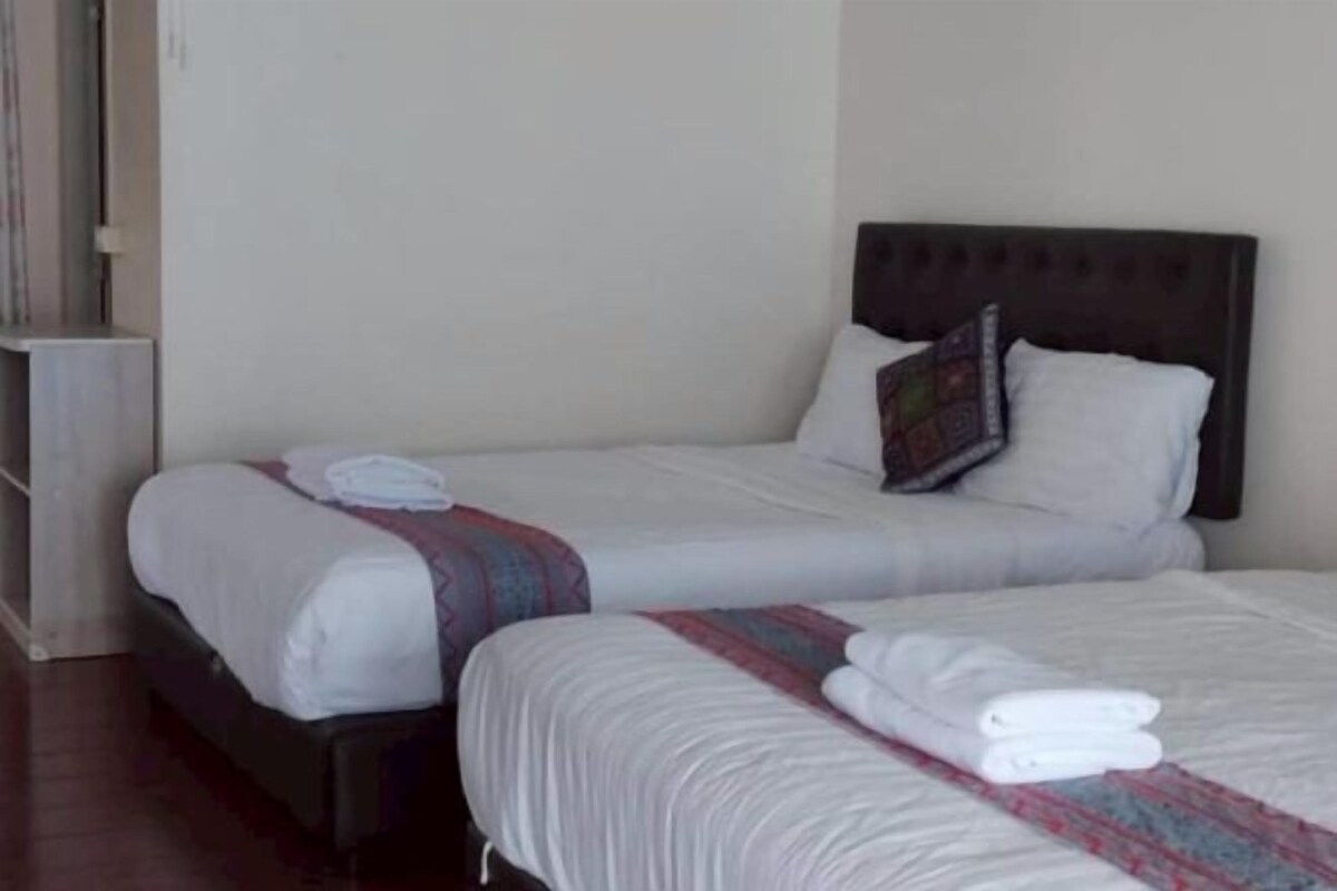A hotel room with two beds, each with white linens and a striped blanket.