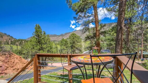 A deck with a table and chairs overlooking a mountainous landscape. - Serenity Pikes Peak Cabin with Hot Tub & Dog Friendly (Cascade-Chipita Park, CO)