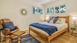 A bedroom with a wooden bed, a leather armchair, a small side table, and a ceiling fan. - Serenity Pikes Peak Cabin with Hot Tub & Dog Friendly (Cascade-Chipita Park, CO)