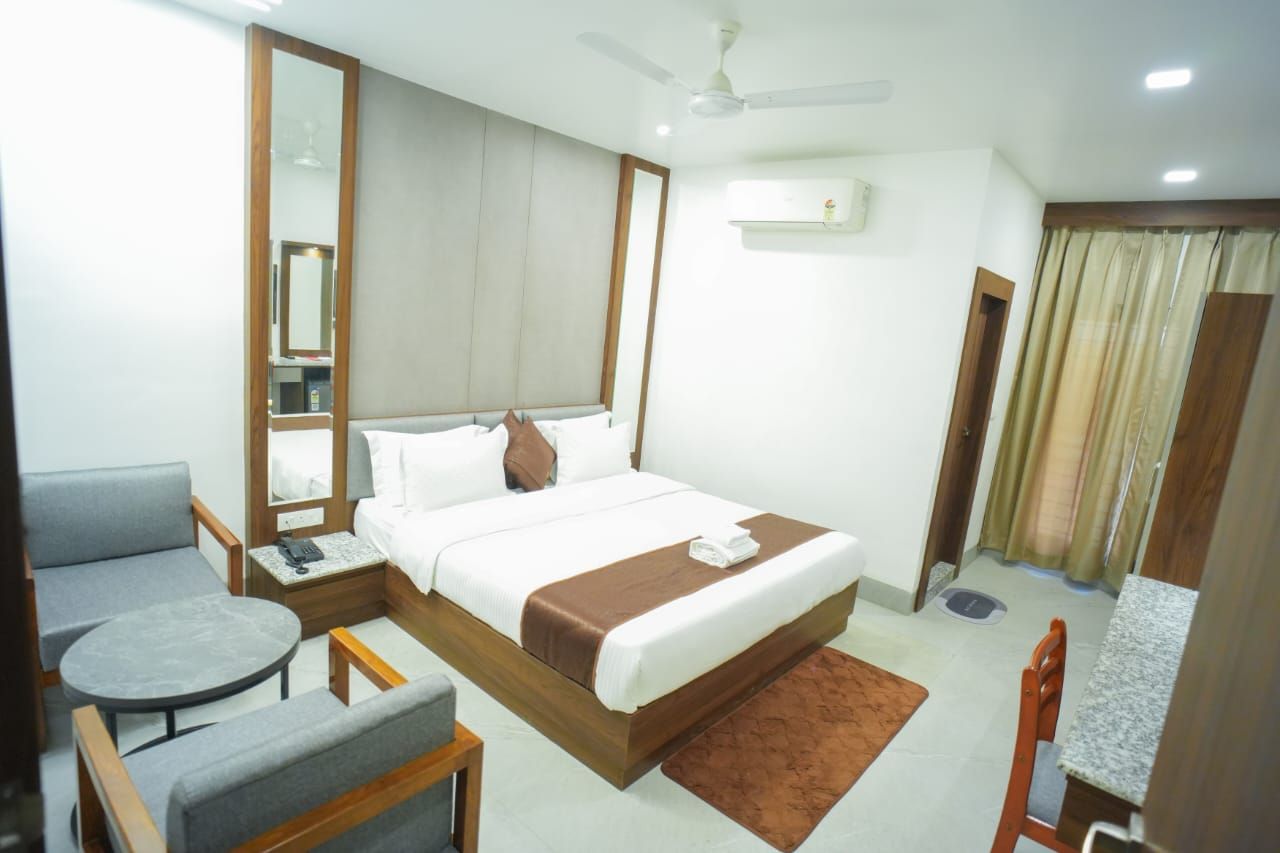 Habitación de hotel con cama, escritorio, silla, mesa redonda y ventilador de techo.