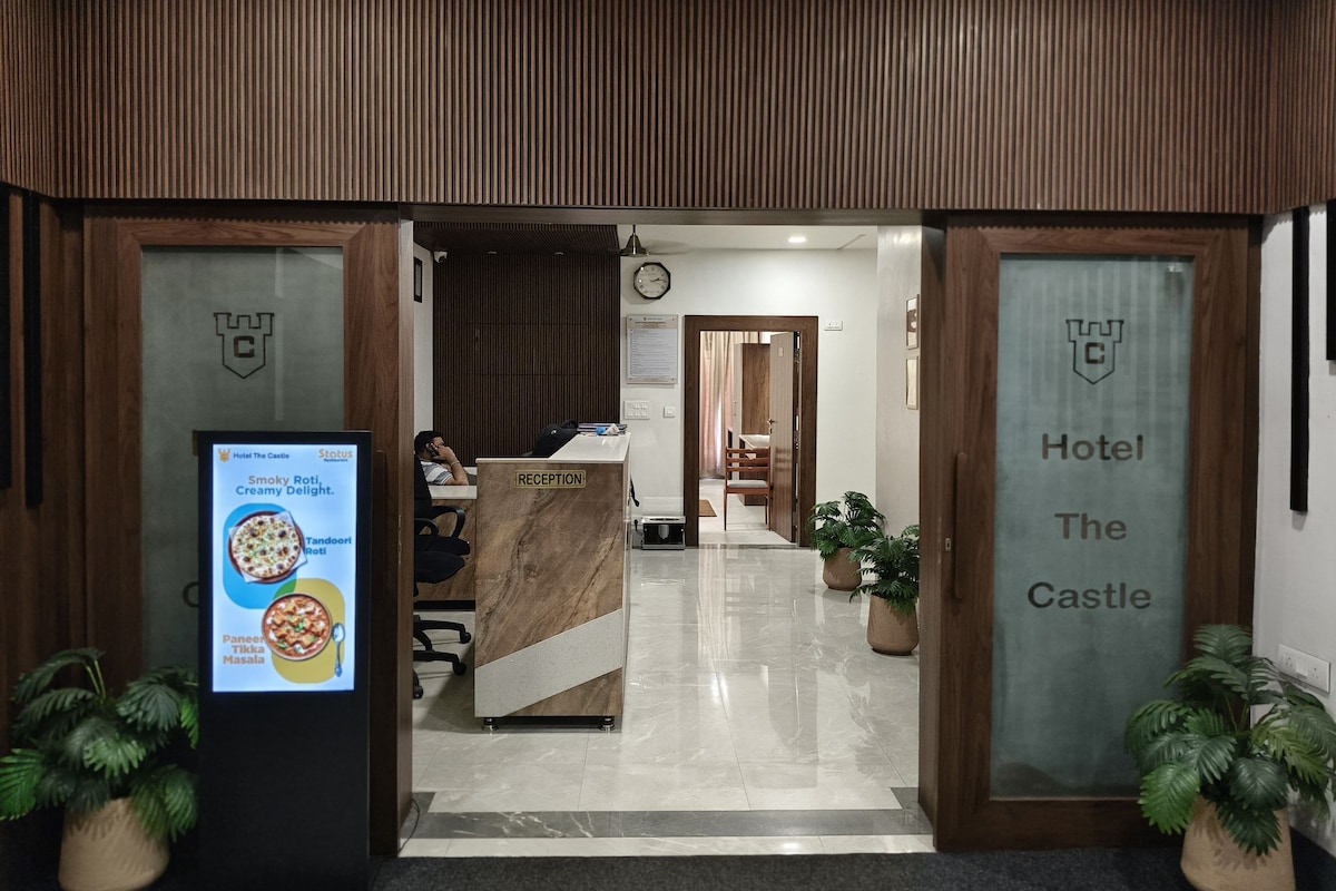 Zona de recepción con mostrador, un reloj y un cartel que indica 'Hotel The Castle'.