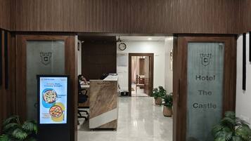 A reception area with a reception desk, a clock, and a sign indicating 'Hotel The Castle'.
