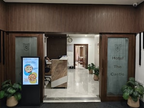 Zona de recepción con mostrador, un reloj y un cartel que indica 'Hotel The Castle'.
