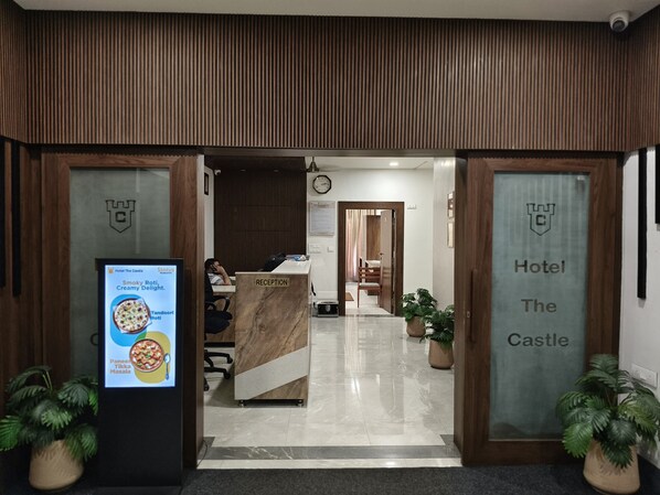 A reception area with a reception desk, a clock, and a sign indicating 'Hotel The Castle'. - Hotel The Castle  (Dhanbad)