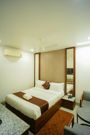 Una habitación de hotel con cama, mesita de noche, silla y espejo.