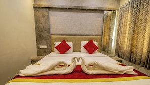 A hotel room with a large bed, two red pillows, and towels arranged in swan shapes. - SR Boutique Stay  (Coimbatore)