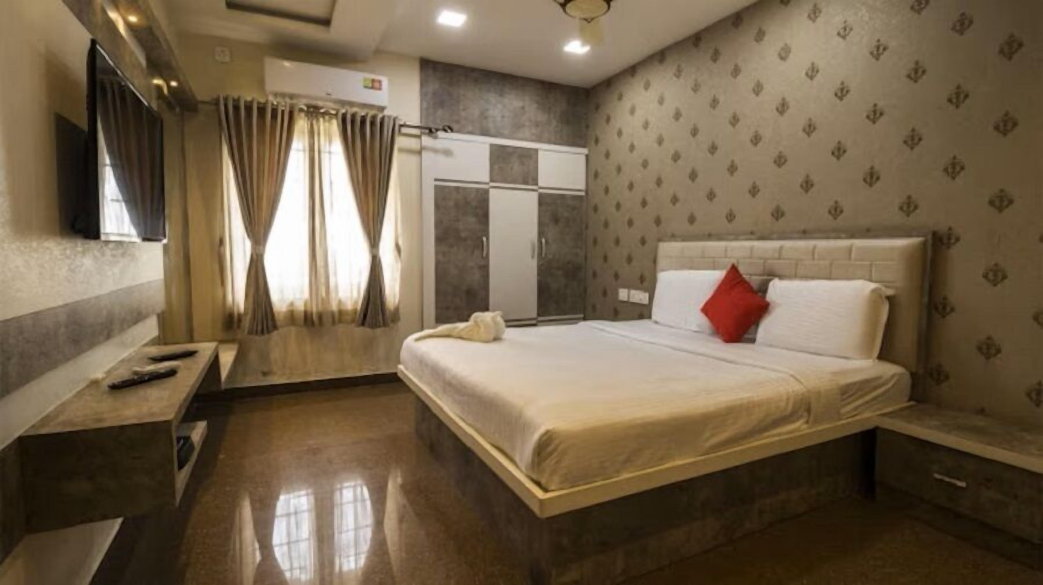A hotel room with a bed, a wardrobe, a vanity with a mirror, and a television.