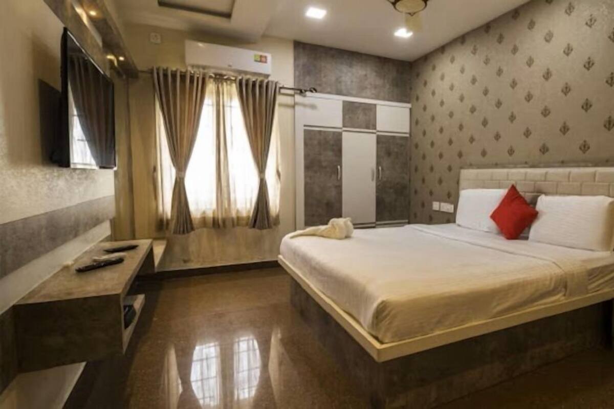 A hotel room with a bed, a wardrobe, a vanity with a mirror, and a television.