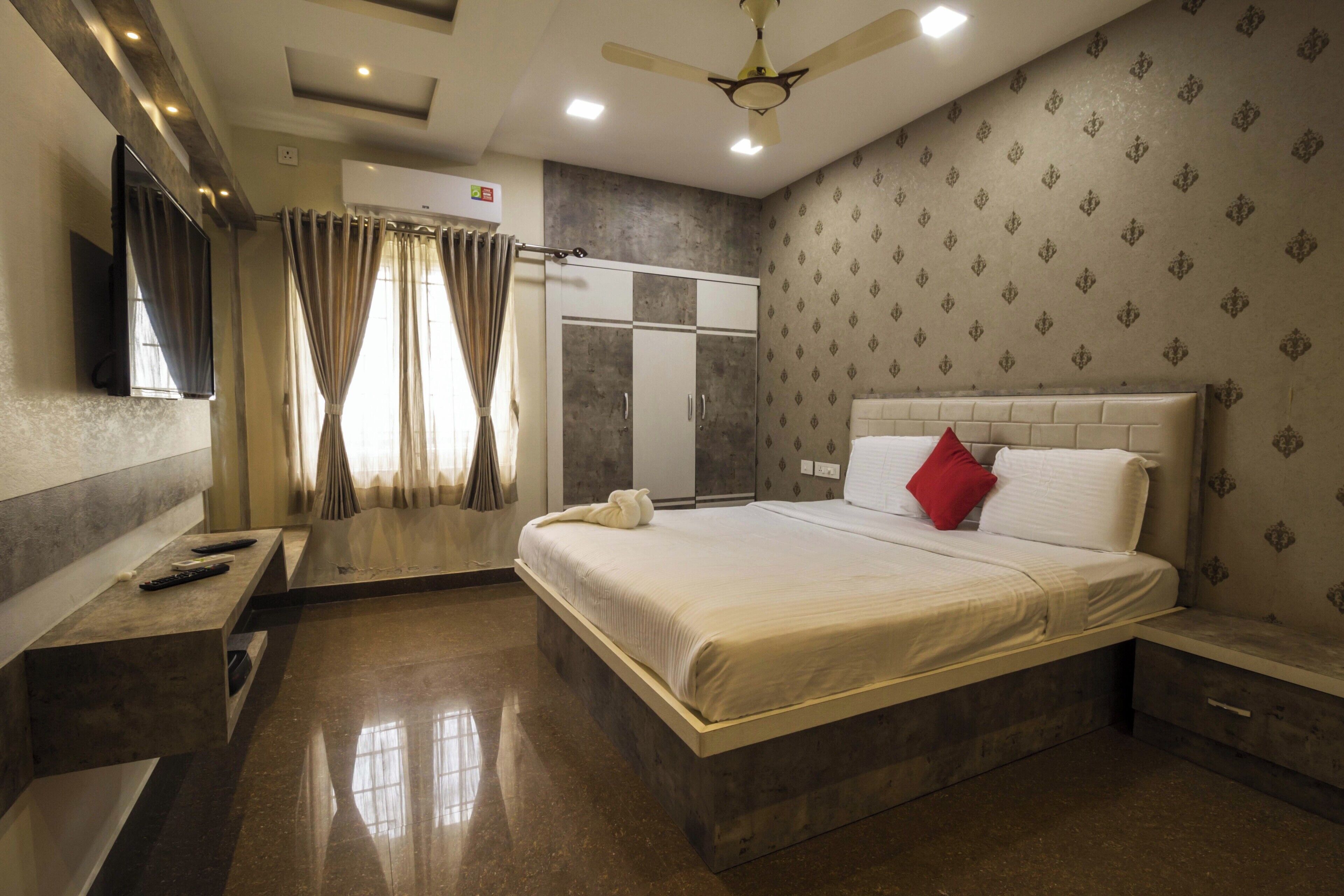 A hotel room with a bed, a vanity with a mirror, a ceiling fan, and a wardrobe.