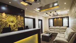 A reception area with a Buddha statue, a sofa, and a coffee table. - SR Boutique Stay  (Coimbatore)