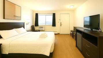 Een hotelkamer met een bed, een televisie, een bureau en een raam.