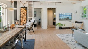 A spacious living area with a high ceiling, a fireplace, a dining table, and a cozy seating area. - "Veljan" - 1.2km from the sea by Interhome (Vig)
