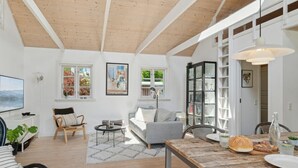 A spacious living area with a wooden ceiling, a grey sofa, a dining table with food, and a bookshelf. - "Veljan" - 1.2km from the sea by Interhome (Vig)