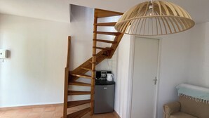 Una scala con ringhiera in legno conduce a un angolo cottura con frigorifero e bollitore.