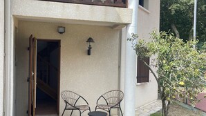 Un edificio a due piani con un balcone, pavimento in pietra e posti a sedere all'aperto.
