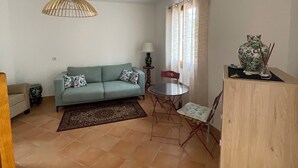 Un soggiorno con un divano, un tavolo da pranzo con sedie, una lampada e un vaso decorativo.