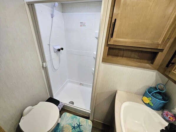 Une petite salle de bain comprenant une douche, des toilettes et un lavabo.