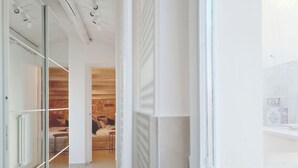 Moderni hotellihuone, jossa on lasiseinä, puukatto ja suuri ikkuna.