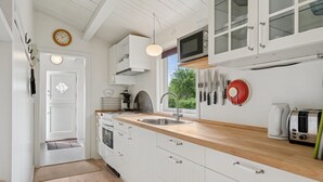 Et moderne køkken med hvide skabe, en træbordplade og et vindue, der giver naturligt lys.