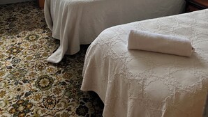 A bedroom with two beds, a window with a view of greenery, a patterned carpet, and a wooden bench. - R2Quiet country setting close to ski fields, Levels Raceway and Fonterra factory (Temuka)