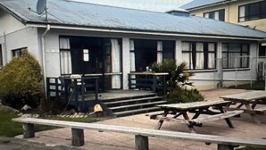 A building with a flat roof, a satellite dish, and a front porch with steps leading to a door. There are picnic tables in the foreground. - R2Quiet country setting close to ski fields, Levels Raceway and Fonterra factory (Temuka)