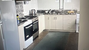 A compact kitchen with white cabinets, a stove, and a refrigerator. - R2Quiet country setting close to ski fields, Levels Raceway and Fonterra factory (Temuka)