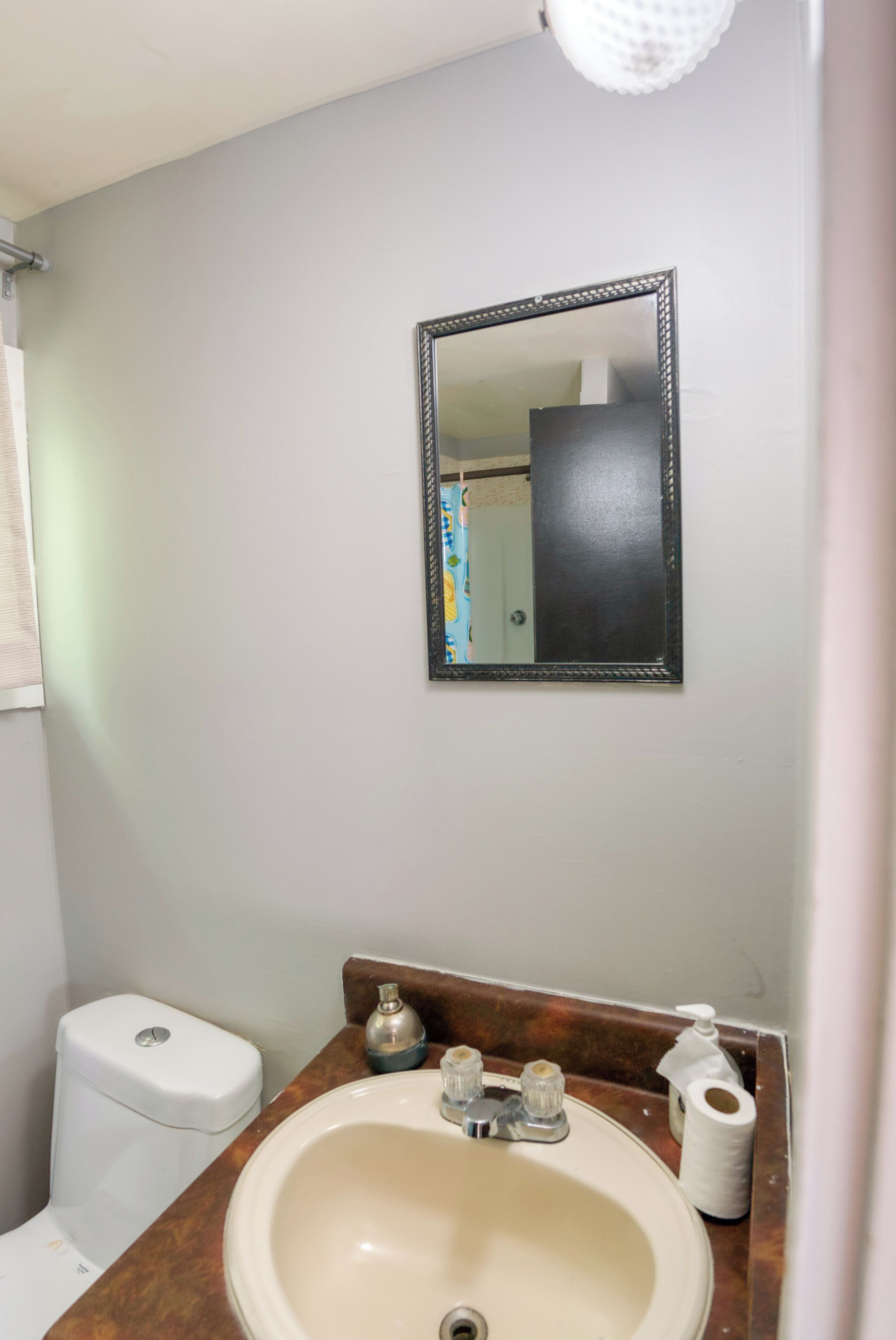 A bathroom with a toilet, sink, and mirror.