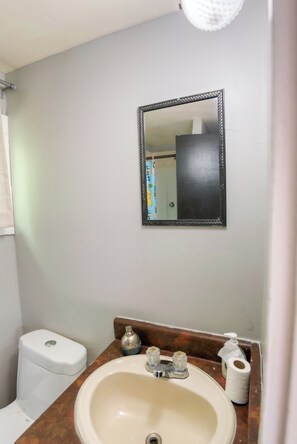 A bathroom with a toilet, sink, and mirror.