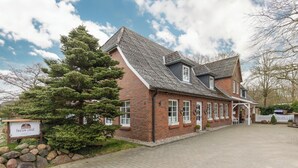 Ein Backsteinhaus mit geneigtem Dach und einer Veranda, mit einem Schild, das es als Lodge kennzeichnet.