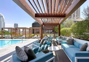 Terraza en la azotea con mobiliario exterior y una piscina, rodeada de edificios de la ciudad.