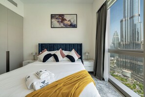 Habitación de hotel con cama, vistas a la ciudad, un cuadro en la pared y una ventana con cortinas.