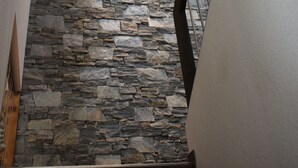 Un escalier avec un mur en pierre et une rampe en métal.