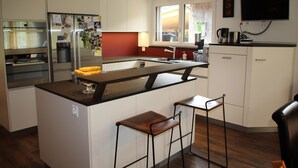 Une cuisine moderne dotée d’un îlot central, de tabourets de bar, d’un réfrigérateur et d’une machine à café.