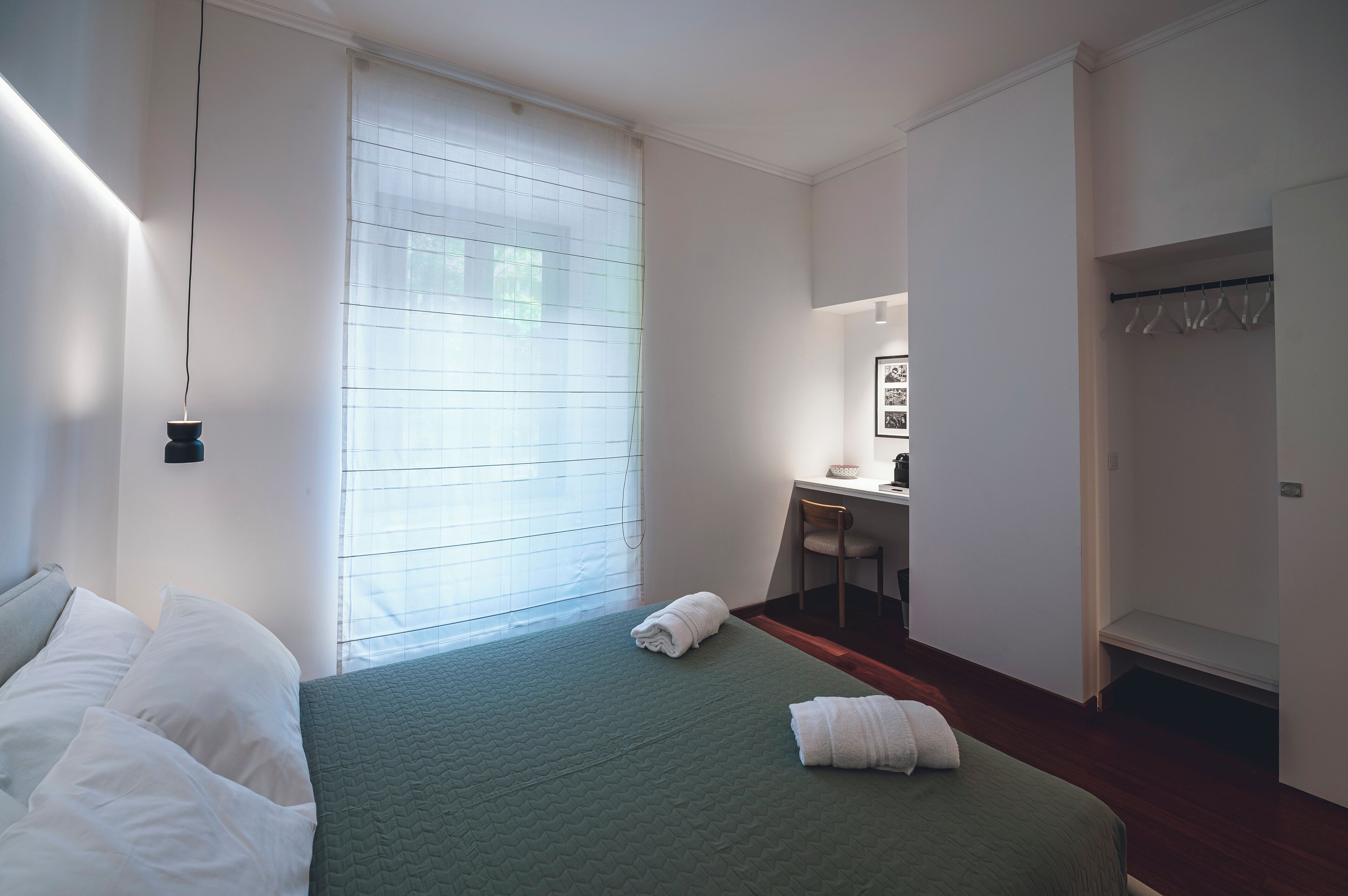 A bedroom with a bed, a desk, and a wardrobe.