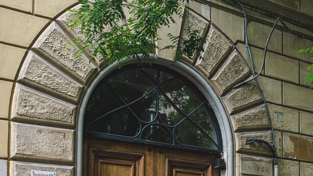 A large wooden double door with a metal frame, set within a stone archway. - Habitat 42 Roman Stay (Rome)