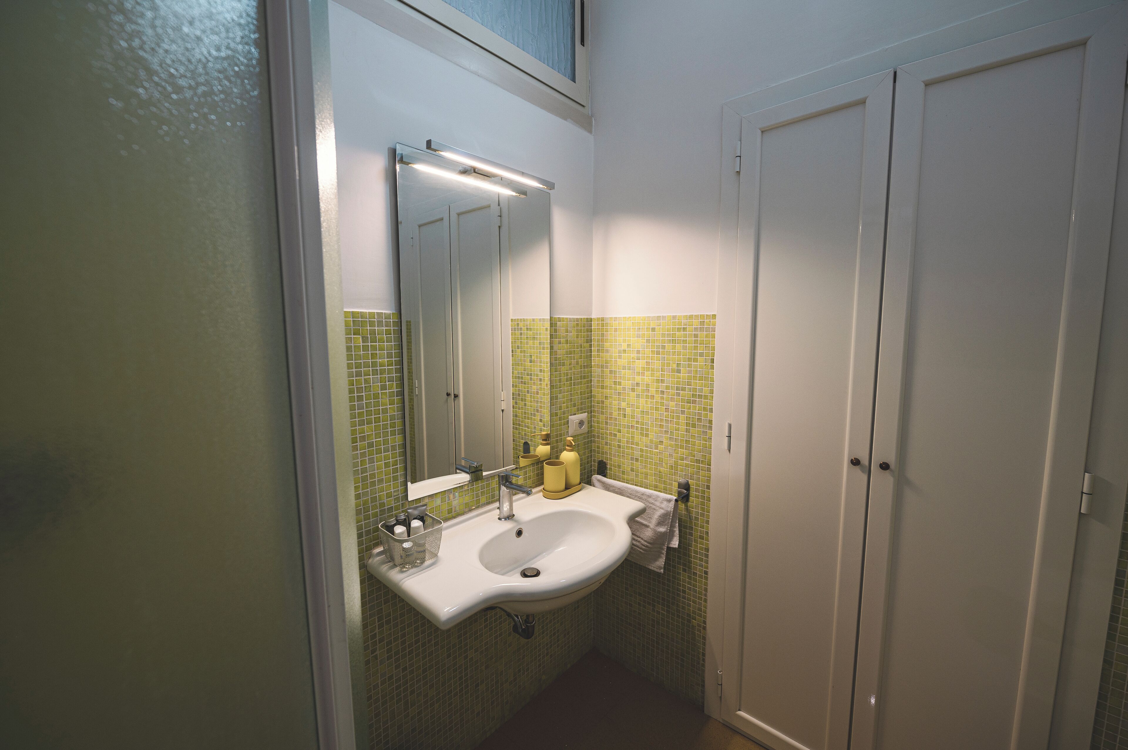 A bathroom with a white sink, mirror, and tiled walls.