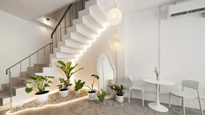 A modern interior with a staircase, potted plants, a white table, and chairs. - Kuha Phuket Old Town (Phuket)