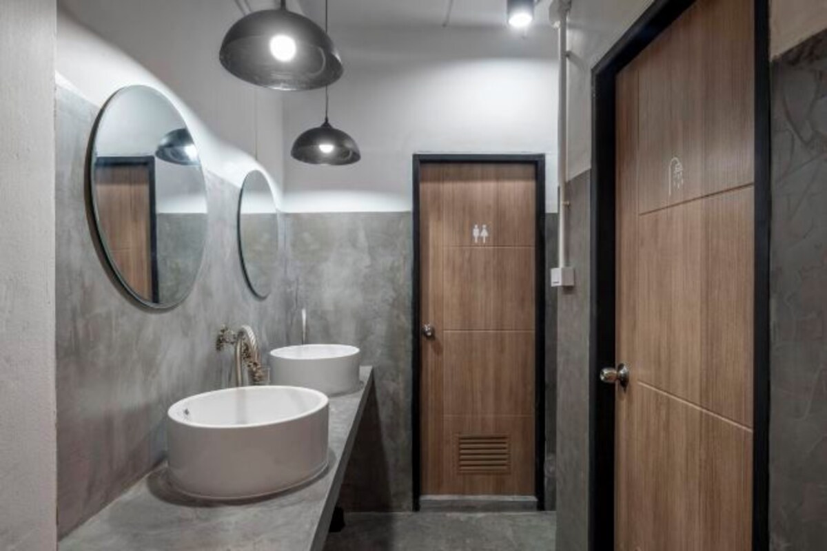 Une salle de bain moderne avec deux vasques, un grand miroir et des luminaires suspendus.