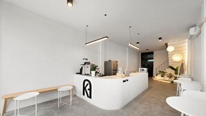 A modern, minimalist kitchen with a central island, white bar stools, and pendant lighting. - Kuha Phuket Old Town (Phuket)