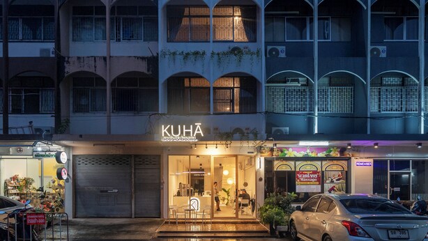 A hotel named "KUHA" with a visible entrance, a closed shop to the left, and a massage service sign to the right. - Kuha Phuket Old Town (Phuket)
