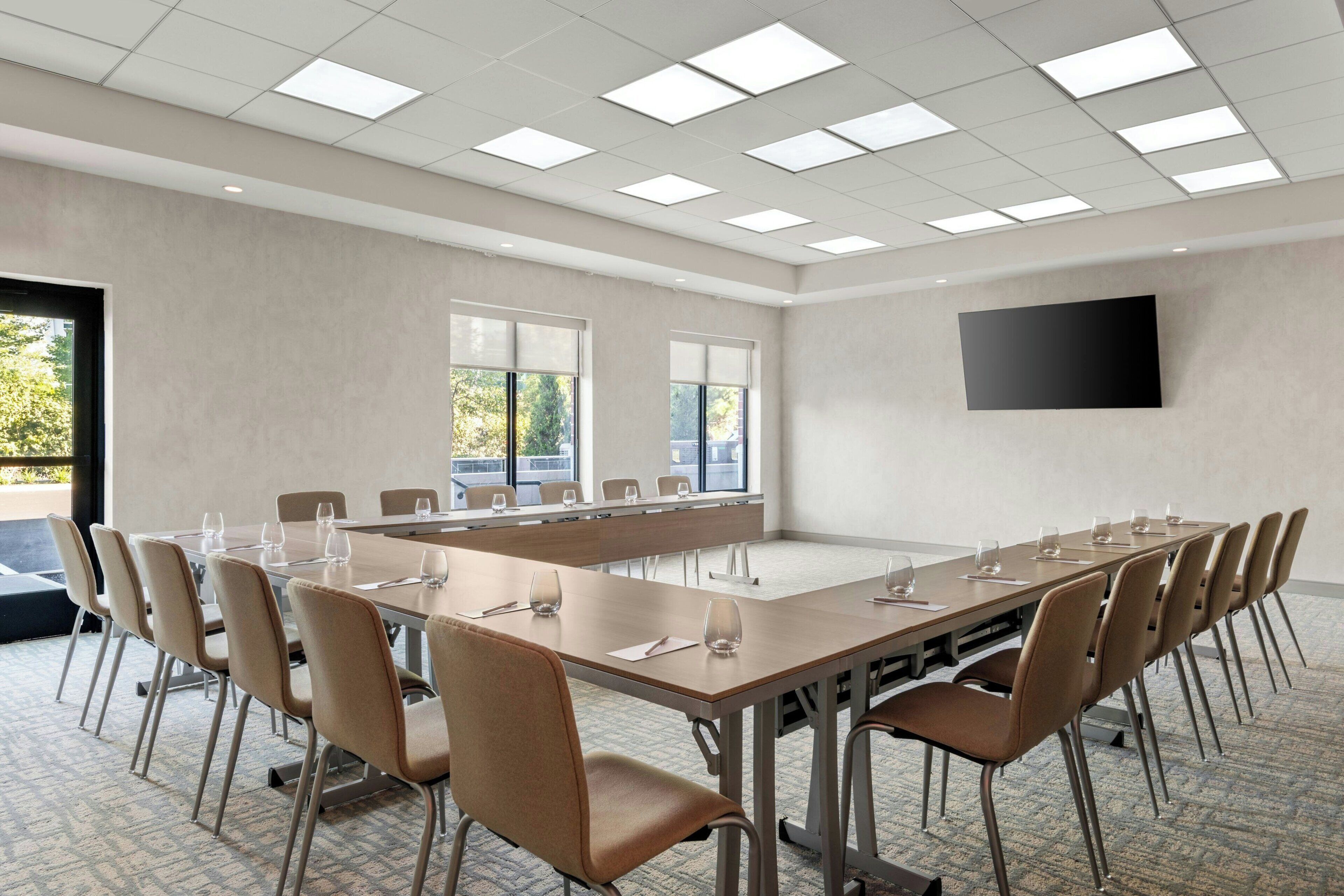 A conference room with a long table, chairs, and a flat-screen TV on the wall.