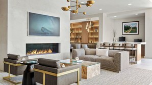 Un salon moderne avec une cheminée, des sièges confortables, un coin repas et une cuisine en arrière-plan.