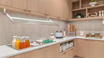 Una cocina moderna con armarios de madera, encimera blanca y diversos alimentos y electrodomésticos.